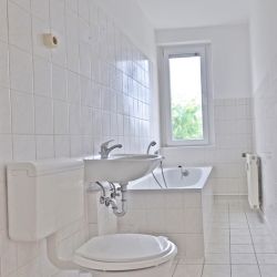 Narrow tiled bathroom with bathtub and window