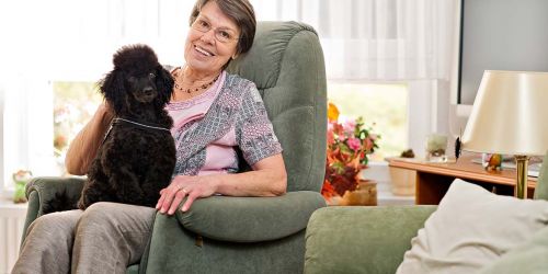 Glückliche Seniorin mit Hund auf dem Schoß