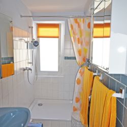 Bright, cozy bathroom with corner shower and curtain